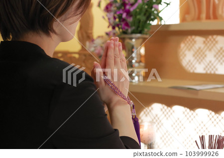 A woman who mourns for the deceased by putting her hands together in front of the altar A woman who mourns for the deceased by putting her hands together in front of the altar 103999926