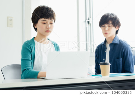 年輕男女一邊看電腦一邊開會 104000355