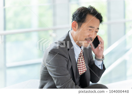 中年商人(老闆、總裁、領導)在辦公室用智能手機交談 中年商人(老闆、總裁、領導)在辦公室用智能手機交談 104000448