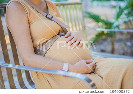 The young pregnant woman has a rest on a bench in park The young pregnant woman has a rest on a bench in park 104000872
