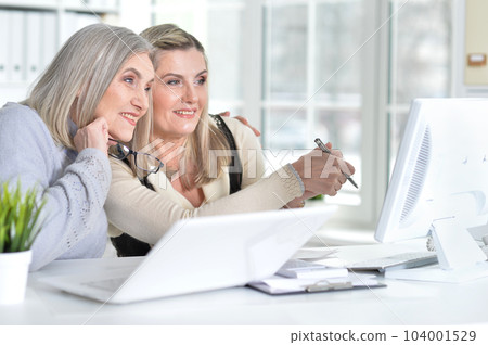 two excited mature women working in office 104001529