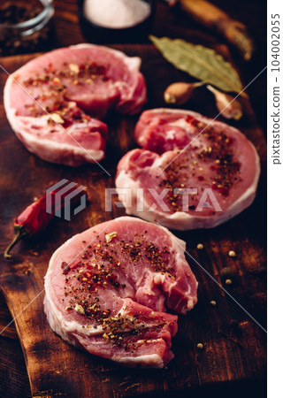 Pork loin steaks with ground spices on cutting board 104002055