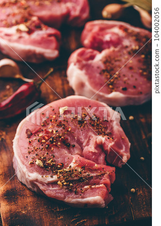 Pork loin steaks with ground spices on cutting board 104002056