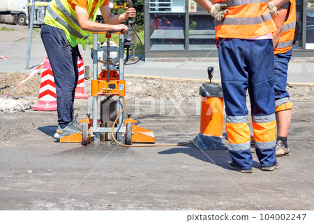 Road workers use a core drilling machine to take cores from an asphalt pavement during road repairs. Road workers use a core drilling machine to take cores from an asphalt pavement during road repairs. 104002247