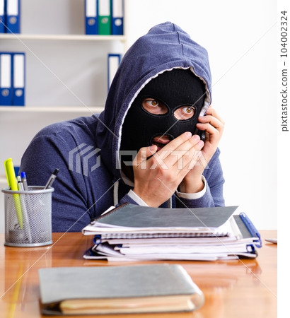 Male thief in balaclava in the office 104002324