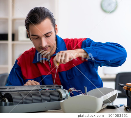 Young repairman repairing air-conditioner at warranty center Young repairman repairing air-conditioner at warranty center 104003361