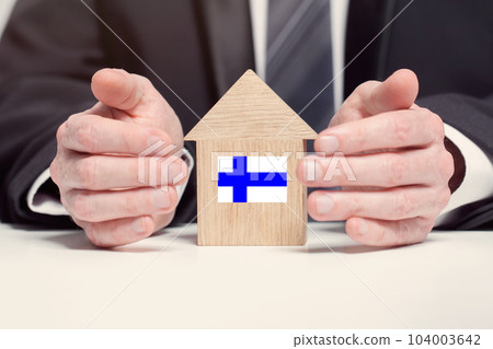 Businessman hand holding wooden home model with Finnish flag. insurance and property concepts Businessman hand holding wooden home model with Finnish flag. insurance and property concepts 104003642