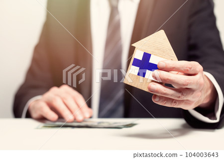 Businessman hand holding wooden Home model with finnish flag. insurance and property concepts Businessman hand holding wooden Home model with finnish flag. insurance and property concepts 104003643