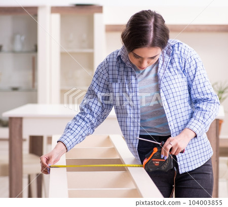 Young beautiful woman assembling furniture at home 104003855