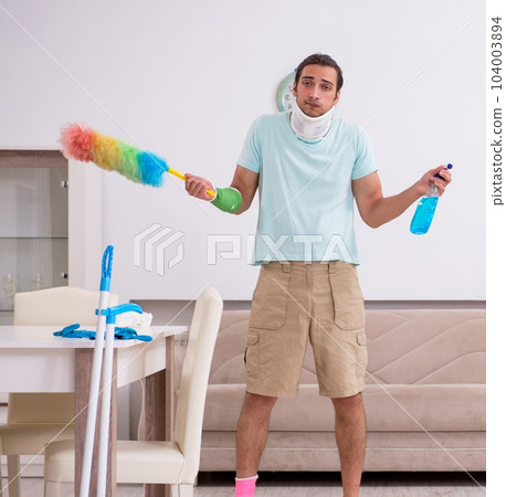 Young injured man cleaning the house 104003894