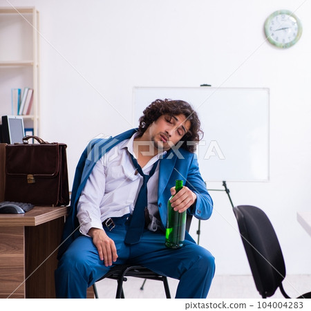 Young drunk employee in the office 104004283