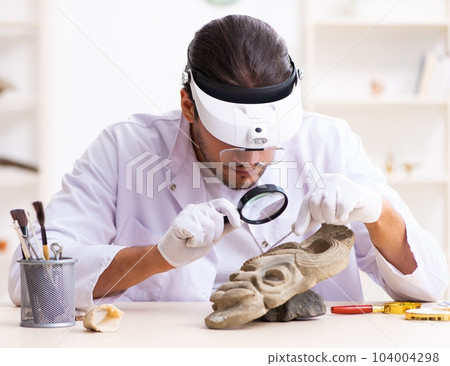 Young male archaeologist studying ancient african stonemask 104004298