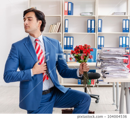Young male employee with bunch of flowers in the office Young male employee with bunch of flowers in the office 104004536