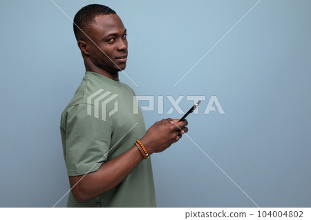 30 year old handsome american man dressed in a basic t-shirt communicates in social networks using a 30 year old handsome american man dressed in a basic t-shirt communicates in social networks using a 104004802