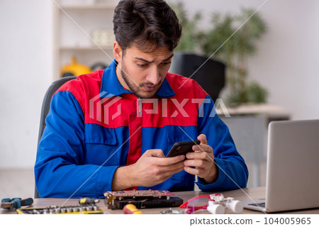 Young male repairman repairing computer Young male repairman repairing computer 104005965