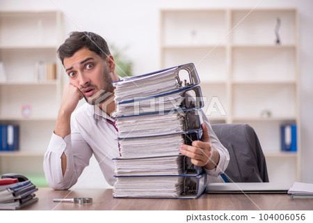 Young male employee and too much work in the office Young male employee and too much work in the office 104006056