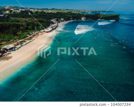 Popular holiday beach in Bali with surfing waves in turquoise ocean. Aerial view 104007284