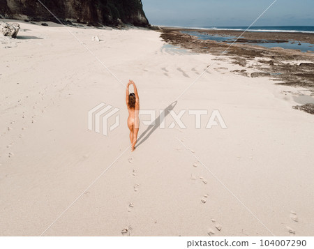 Naked woman sunbathing at paradise beach near ocean. Aerial view Naked woman sunbathing at paradise beach near ocean. Aerial view 104007290