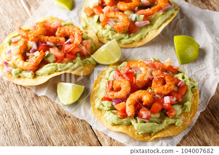 Tostadas with shrimps, tomato salsa and guacamole close-up on a table. Horizontal Tostadas with shrimps, tomato salsa and guacamole close-up on a table. Horizontal 104007682