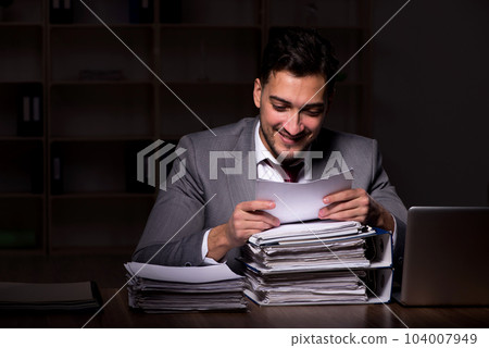 Young male employee working late in the office 104007949