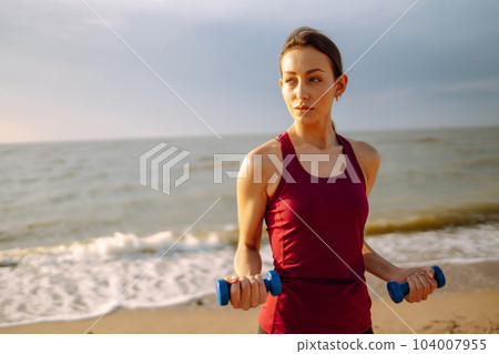 Young woman in sportswear doing yoga, fitness exerciseon the beach. Sport, Active life. 104007955