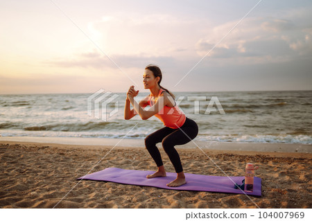 Young woman in sportswear doing yoga, fitness exerciseon the beach. Sport, Active life. 104007969