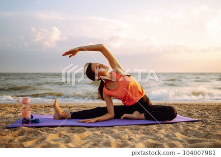 Young woman in sportswear doing yoga, fitness exerciseon the beach. Sport, Active life. 104007981