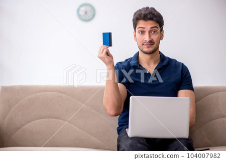 Young man ordering goods via Internet at home 104007982