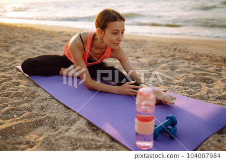 Young woman in sportswear doing yoga, fitness exerciseon the beach. Sport, Active life. Young woman in sportswear doing yoga, fitness exerciseon the beach. Sport, Active life. 104007984