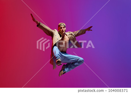 Active, artistic young man in casual clothes dancing breakdance, contempt against pink purple studio background Active, artistic young man in casual clothes dancing breakdance, contempt against pink purple studio background 104008371