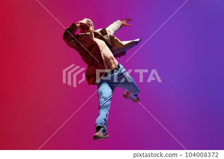 Active, artistic young man in casual clothes dancing breakdance, contempt against pink purple studio background Active, artistic young man in casual clothes dancing breakdance, contempt against pink purple studio background 104008372