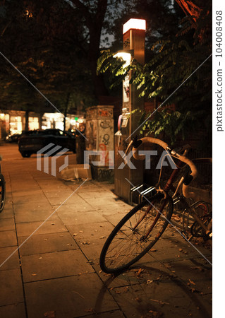 Vertical view of a bicycle parked on the sidewalk in the evening Vertical view of a bicycle parked on the sidewalk in the evening 104008408