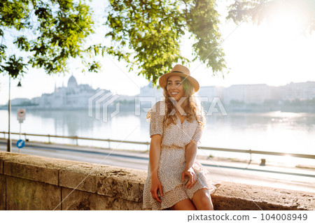 Young female tourist enjoys view of city at sunset. Euro-trip. Travel, tourism, lifestyle concept. Young female tourist enjoys view of city at sunset. Euro-trip. Travel, tourism, lifestyle concept. 104008949