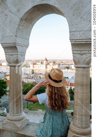 Female tourist looking at panoramic view of city at sunset. Lifestyle, travel, tourism, nature. 104008954
