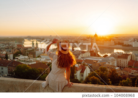 Young female tourist enjoys view of city at sunset. back view Lifestyle, travel, nature, active life 104008968