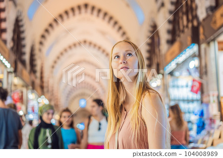 A tourist woman walks among the countless shops at the Grand Bazaar and Egyptian Bazaar in Istanbul. Shopping and travel in Turkey concept. Istanbul historical Egyptian Bazaar. Misir Carsisi, spice A tourist woman walks among the countless shops at the Grand Bazaar and Egyptian Bazaar in Istanbul. Shopping and travel in Turkey concept. Istanbul historical Egyptian Bazaar. Misir Carsisi, spice 104008989
