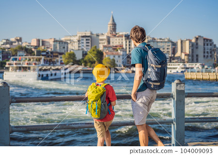 Father and son tourists enjoy Istanbul city skyline in Turkey, Beyoglu district old houses with Galata tower on top, view from the Golden Horn 104009093
