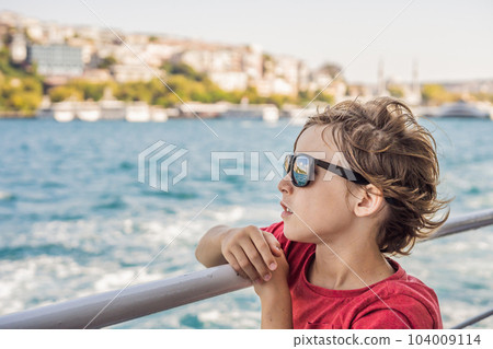 Happy boy enjoying the sea from ferry boat crossing Bosphorus in Istanbul. Summer trip to Istanbul. Traveling with kids concept Happy boy enjoying the sea from ferry boat crossing Bosphorus in Istanbul. Summer trip to Istanbul. Traveling with kids concept 104009114