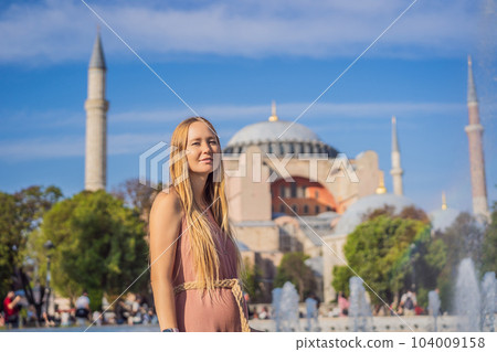 Woman enjoy beautiful view on Hagia Sophia Cathedral, famous islamic Landmark mosque, Travel to Istanbul, Turkey. Sunny day architecture and Hagia Sophia Museum, in Eminonu, istanbul, Turkey. Turkiye 104009158