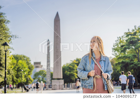 Woman Tourist in Istanbul against the background of Obelisk of Theodosius is the Ancient Egyptian obelisk of Pharaoh Thutmose III places in the Hippodrome of Constantinople, Turkey. Theodosius Woman Tourist in Istanbul against the background of Obelisk of Theodosius is the Ancient Egyptian obelisk of Pharaoh Thutmose III places in the Hippodrome of Constantinople, Turkey. Theodosius 104009177