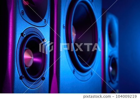 Multimedia acoustic sound speakers with neon lighting. Sound audio system with two satellites and subwoofer on dark background. Multimedia acoustic sound speakers with neon lighting. Sound audio system with two satellites and subwoofer on dark background. 104009219