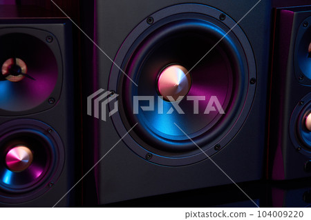 Multimedia acoustic sound speakers with neon lighting. Sound audio system with two satellites and subwoofer on dark background. 104009220