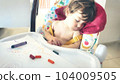 A little baby boy toddler asleep in his high-chair after playing with colored crayons 104009505