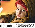 A young white Caucasian boy wearing thick winter clothes looking directly at the camera 104009508