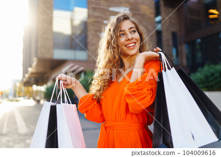 Shopping woman. Young woman with shopping bags in the city. Vacation, sale or purchase concept. Shopping woman. Young woman with shopping bags in the city. Vacation, sale or purchase concept. 104009616