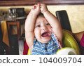 Young child throwing a tantrum in her high chair in a restaurant 104009704