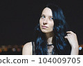 Portrait headshot of an attractive white Caucasian young woman with striking features against a night time dark background 104009705