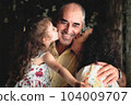 3 generations lifestyle portrait shot - a woman and her daughter kissing the father / grandfather - white Caucasian family celebrating a happy moment of affection 104009707