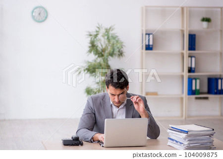 Young male employee and too much work in the office 104009875