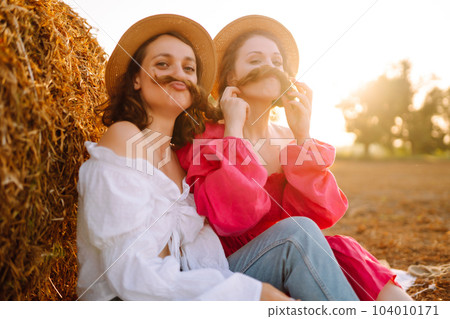 Two young women having fun near haystack. Fashion concept. Summer concept. Two young women having fun near haystack. Fashion concept. Summer concept. 104010171